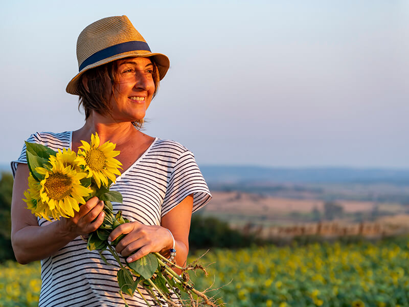 A woman holding sunflowers in a farm Sceladerma Queensland Support Group Members Stories